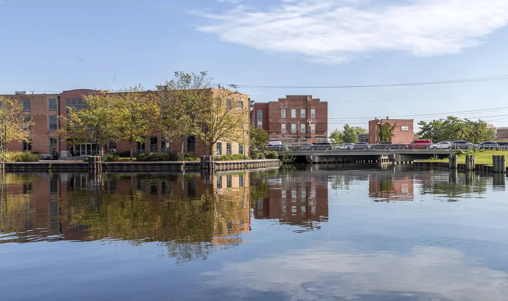 Brick waterfront buildings and a bridge reflected in the Wicomico River at Salisbury